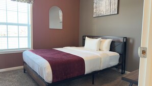 Un dormitorio con cama, ventana y un cuadro en la pared.