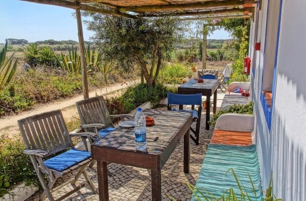 An outdoor patio with a table and chairs, surrounded by plants and a view of the countryside.