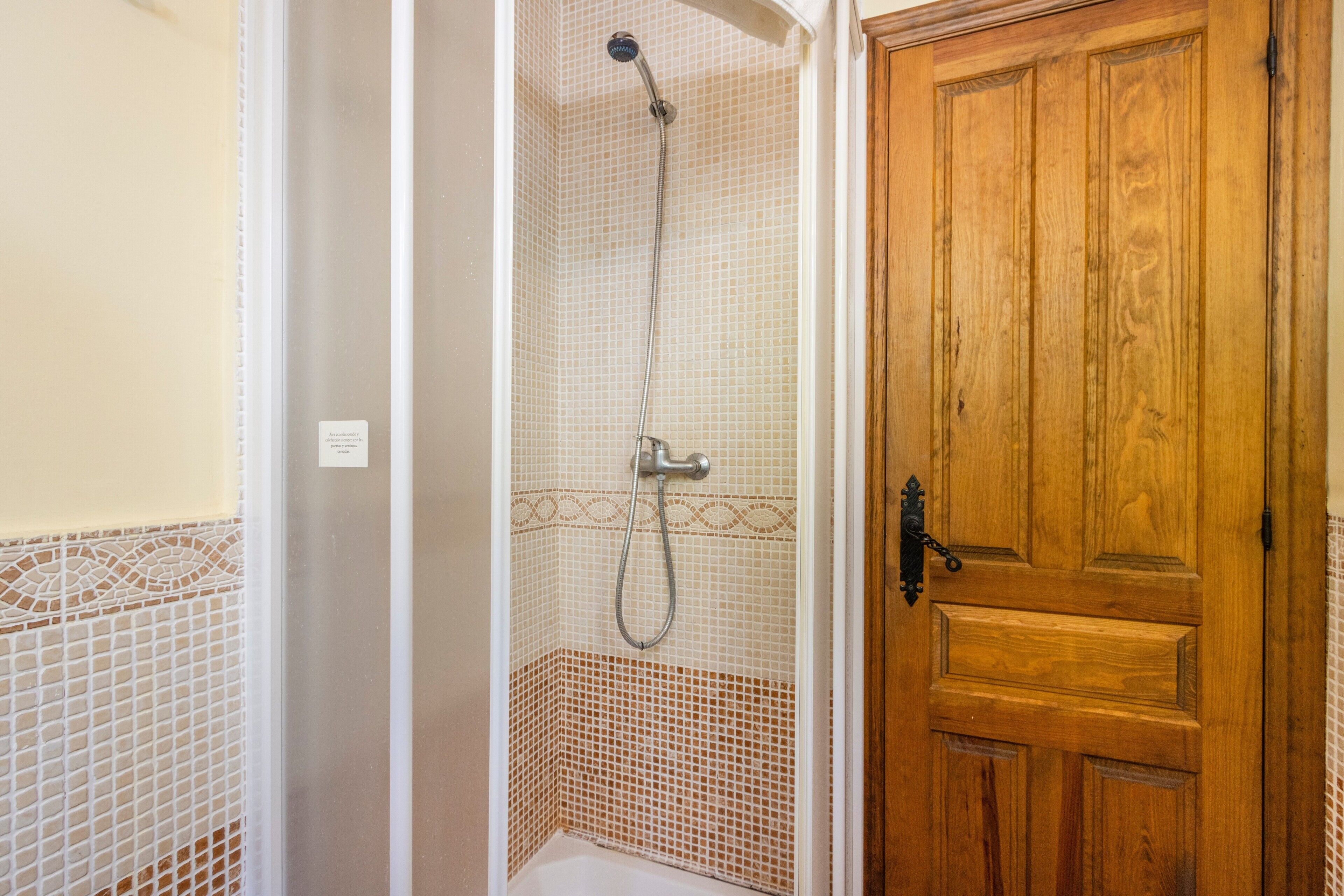 Ein Badezimmer mit Dusche, Holztür und gefliesten Wänden.