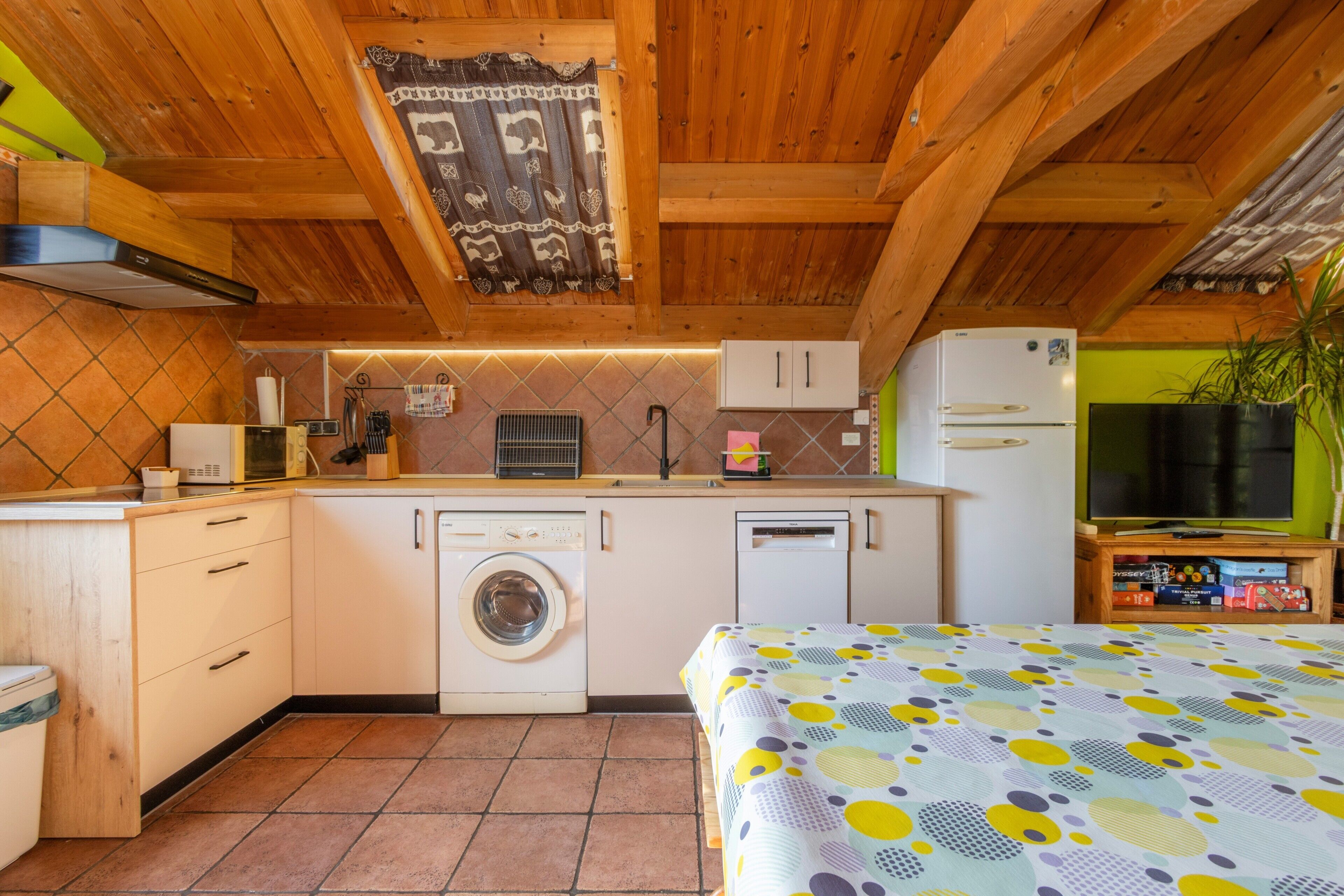 Een kleine keuken met een wasmachine, een magnetron en een koelkast.