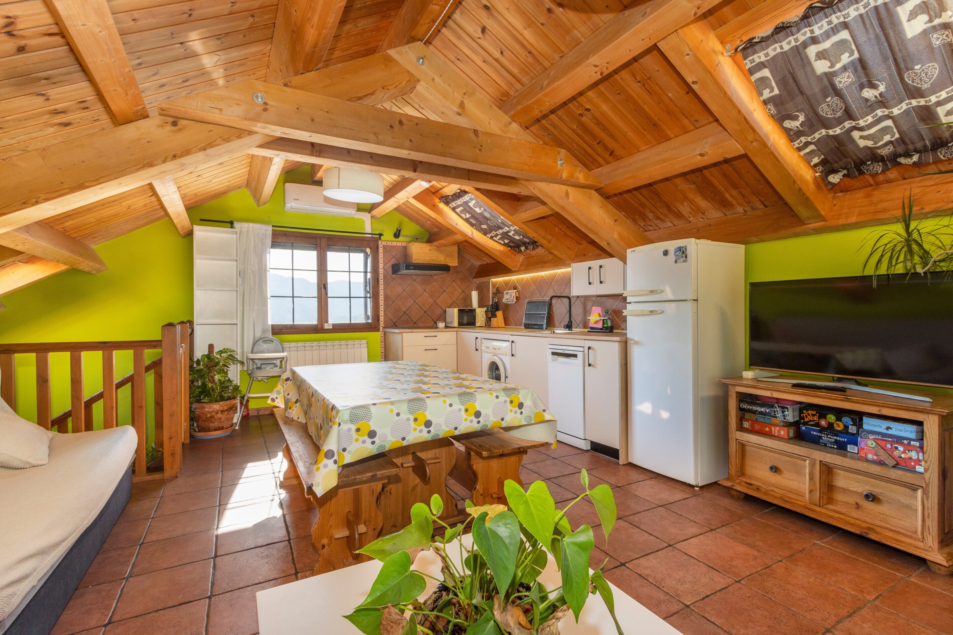 Une chambre mansardée agréable, avec un lit, une table à manger, une cuisine équipée d’un téléviseur et un balcon.