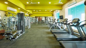 A gym with cardio equipment, weight machines, and mirrors. - Club Anandam (Raipur)