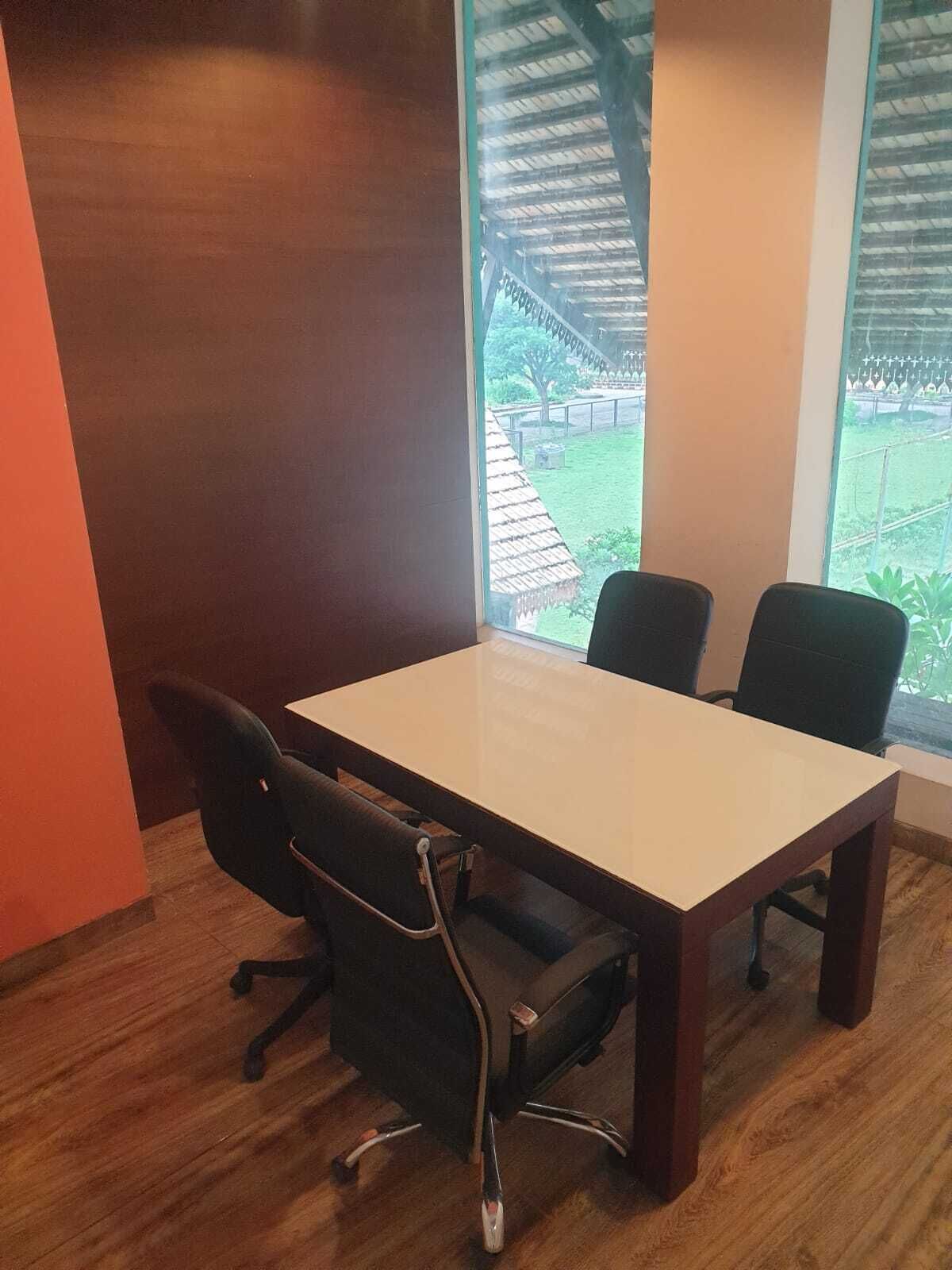 Ein Konferenzraum mit einem Holztisch und vier Stühlen.