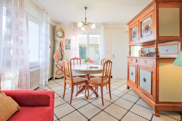 Un coin repas avec une table ronde, des chaises, un canapé rouge, un meuble en bois et un radiateur.
