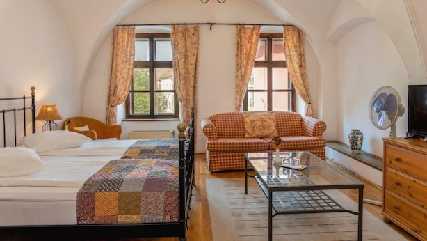 Une chambre à coucher comprenant un lit, un canapé, une table basse en verre, une commode et un lustre.