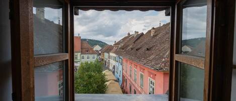 Una ventana estrecha con vistas a edificios coloridos y un árbol en primer plano.