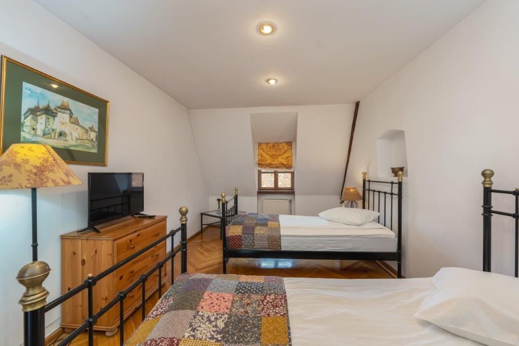 Un dormitorio con dos camas, un aparador de madera, un televisor y un cuadro en la pared.