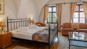 Une chambre à coucher avec un lit, une table de chevet, une lampe, un canapé et une fenêtre avec des rideaux.