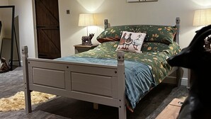 A bedroom with a bed, a wooden door, a lamp, and a painting on the wall. - Luxury Country Lodge in Bretherton -sleeps 1 Double bed & 1 bed Settee (Leyland)