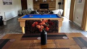 A pool table with a floral centerpiece, a sofa, and a television in a living room. - Luxury Country Lodge in Bretherton -sleeps 1 Double bed & 1 bed Settee (Leyland)