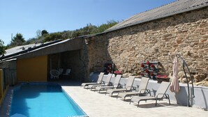 Une piscine avec des chaises longues et un mur en pierre.