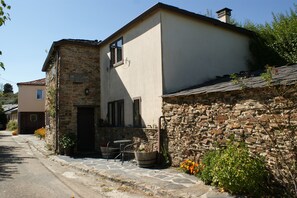 A stone building with a sign, a door, and a small outdoor seating area with a table and chairs.