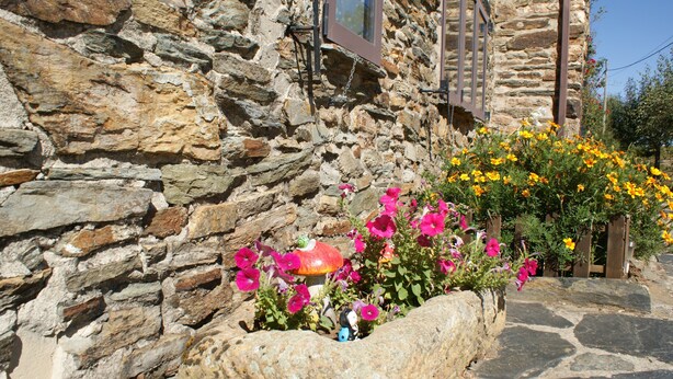 Un bâtiment en pierre avec un parterre de fleurs devant.