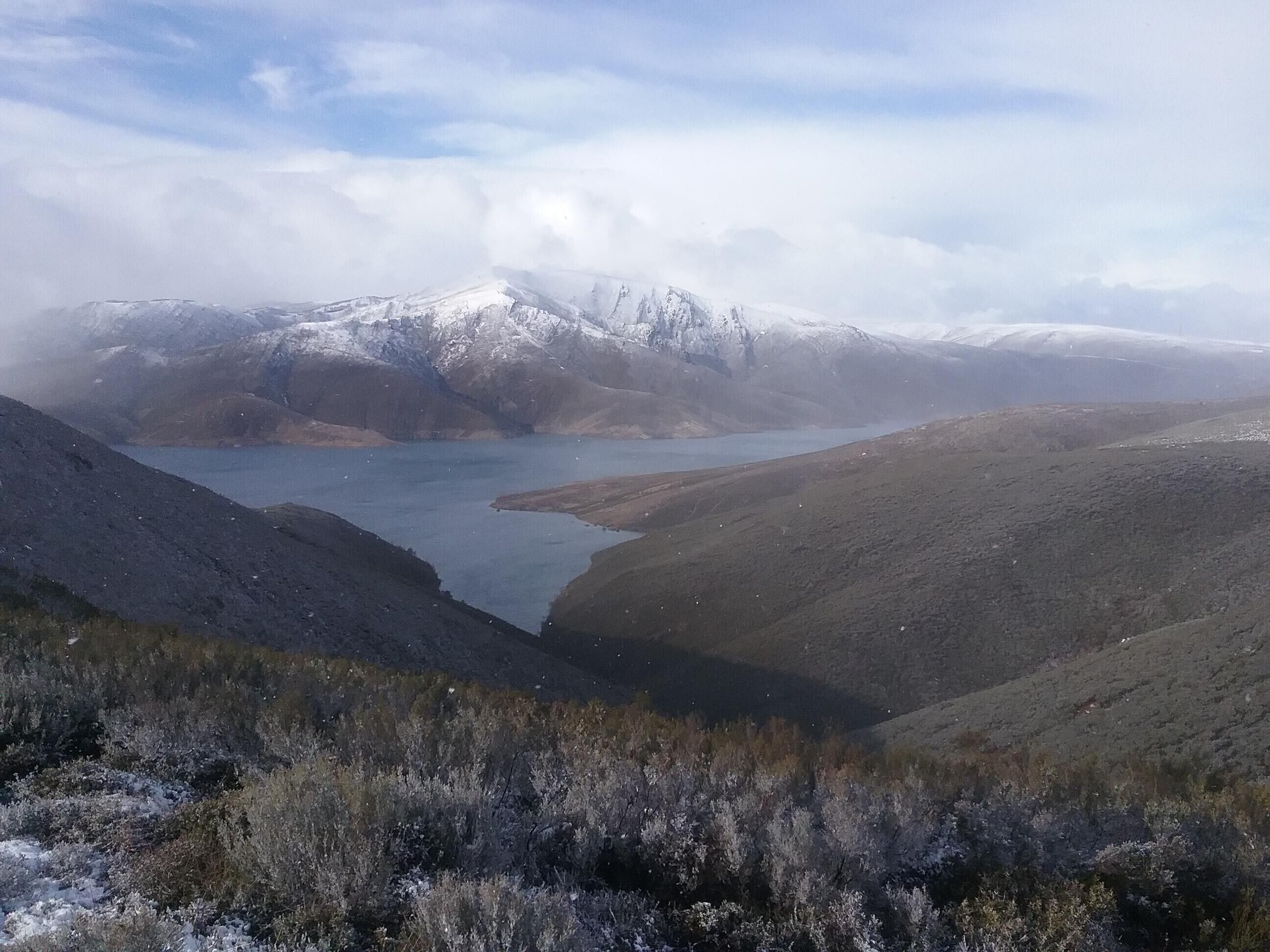 Paisaje montañoso con un lago y picos nevados.