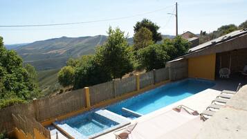 Piscina con vistas a colinas, zona de estar cubierta y un perímetro cercado.
