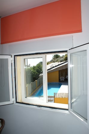 Une pièce avec une fenêtre, une porte blanche et un mur rouge.