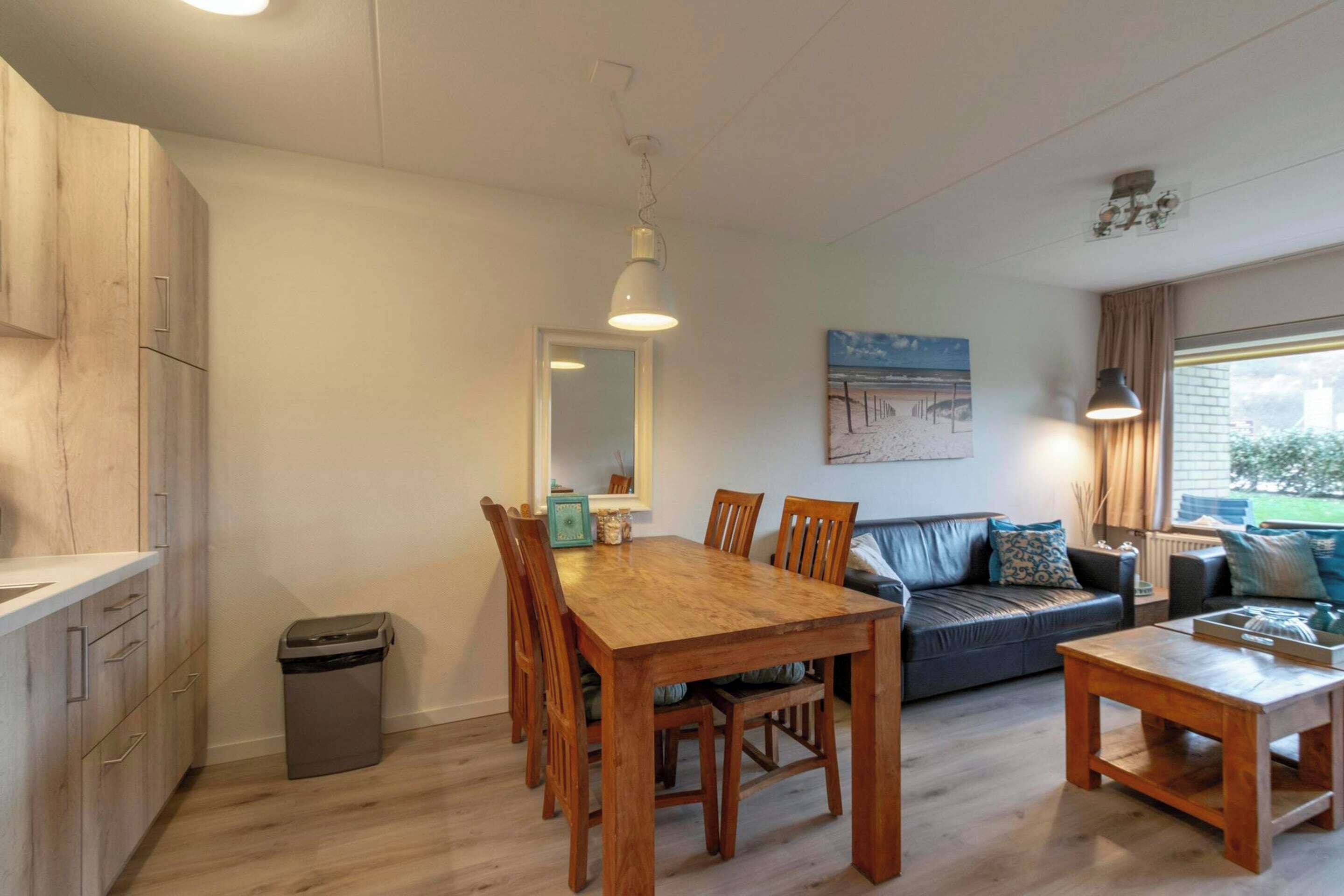A compact living space with a dining area, a sofa, and a small kitchen.