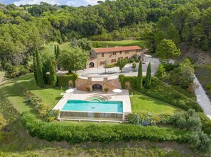 A stone villa with a swimming pool, surrounded by lush greenery and a hilly landscape. - Villa 'Cava Alta' with Sea View, Wi-Fi and Air Conditioning (Riparbella)