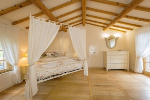 A bedroom with a four-poster bed, a dresser, a mirror, and a window with curtains. - Villa 'Cava Alta' with Sea View, Wi-Fi and Air Conditioning (Riparbella)