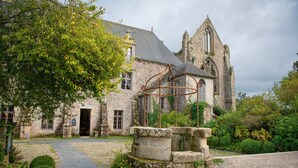 A stone building with a Gothic architectural style, a cobblestone pathway, and a metal structure in the foreground.