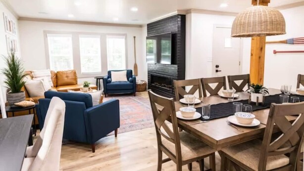 A modern living room with a sofa, a dining table set for four, and a fireplace. - The Ridge House-Lake House w/Hot Tub & Game Room-DOG friendly (Eureka Springs)