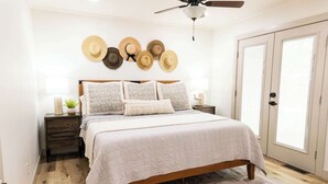 A bedroom with a bed, a nightstand, a wall-mounted hat display, and a door. - The Ridge House-Lake House w/Hot Tub & Game Room-DOG friendly (Eureka Springs)