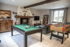 Ein Raum mit Billardtisch, Kicker, Kamin und Fernseher.