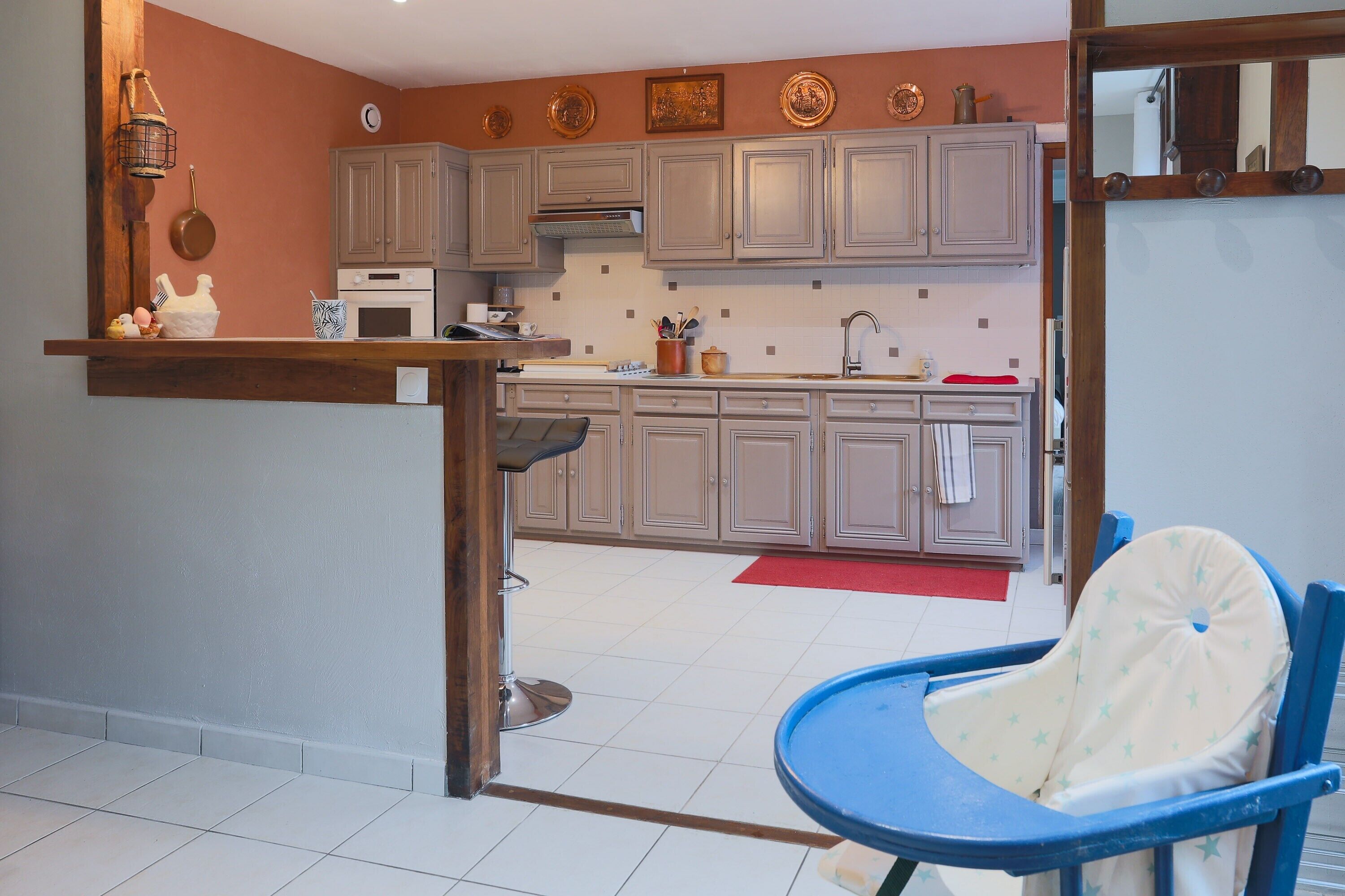 A kitchen with grey cabinets, a stove, and a blue chair.