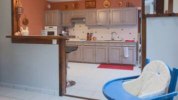 A kitchen with grey cabinets, a stove, and a blue chair.
