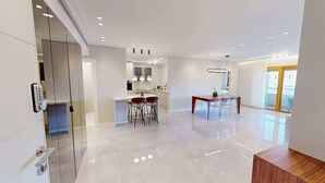 A modern kitchen with a central island, bar stools, and a dining table with chairs. - King David Residences: Spacious 3-bdrs 3-bths with Pool, Gym & View in Jerusalem (Jerusalem)