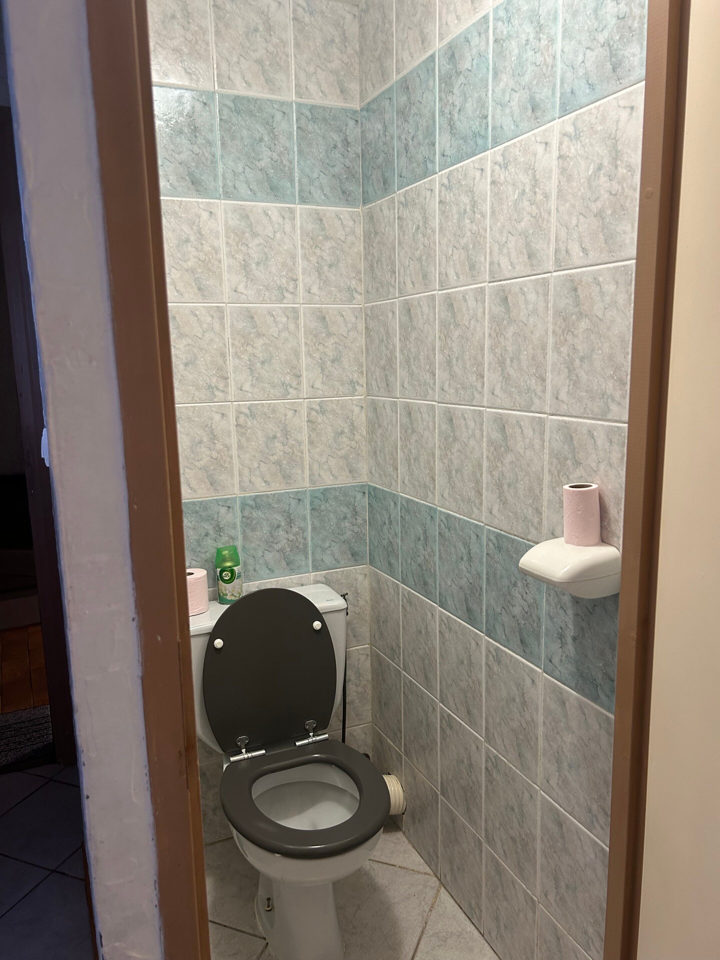 A small bathroom with a toilet, a toilet paper holder, and a paper towel dispenser.