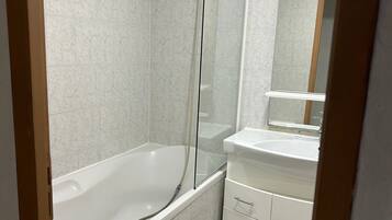 A bathroom with a bathtub, a shower, a sink, and a mirror.