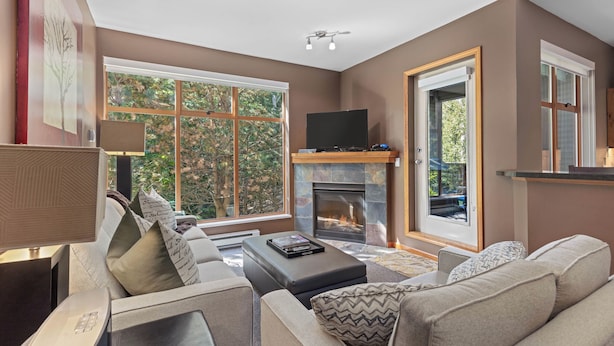 A modern living room with a fireplace, large windows, and comfortable seating.