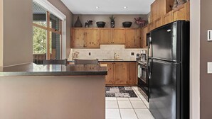 A kitchen with wooden cabinets, a black refrigerator, and a window providing natural light.