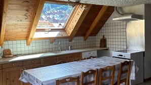 A kitchen with a wooden table and chairs, a window with a view, and a tiled backsplash.