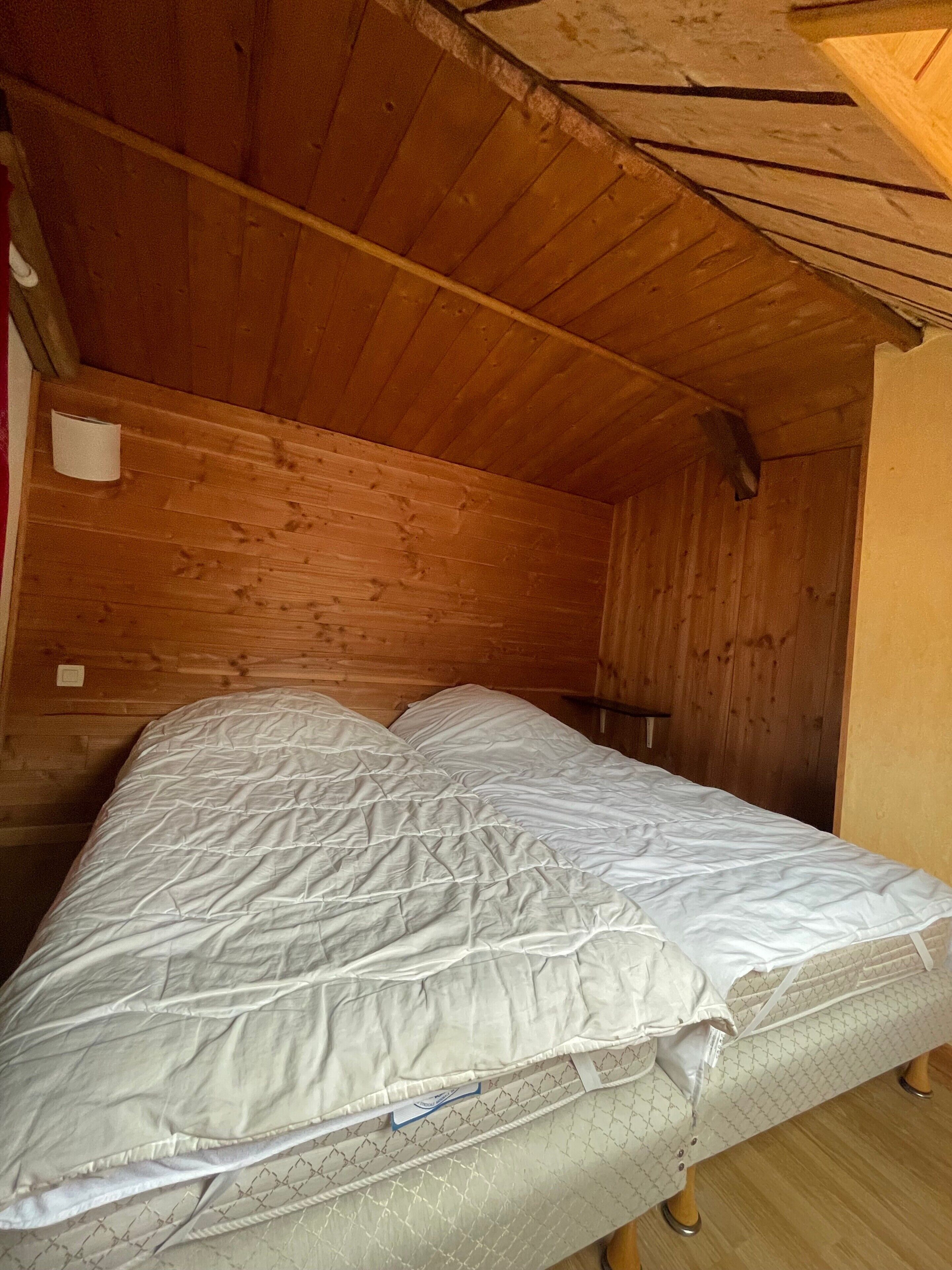 Una cama individual en una habitación de cabaña de madera con techo inclinado.