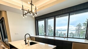 Eine moderne Küche mit einer großen Kochinsel, Barhocker und Blick ins Freie.