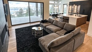 Ein modernes Wohnzimmer mit einem Ecksofa, einem schwarzen Teppich und einem Glastisch.