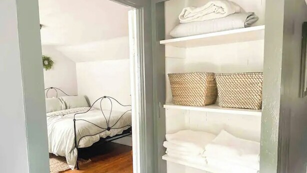 Ein Schlafzimmer mit einem Bett, einem weißen Kleiderschrank mit Einlegeböden und einem Korb.