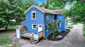 Ein blaues, zweistöckiges Haus mit einer Veranda und einem kleinen Gartenhaus.