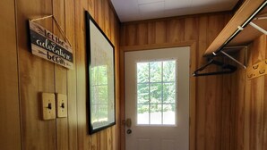 A wooden interior hallway with a white door, a window, and a sign on the wall. - Green Cabin in the Woods (Irons)