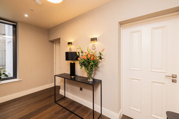 A hallway with a black console table, a vase with flowers, and a white door.