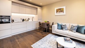 Una cocina moderna con muebles blancos, un comedor con una mesa redonda y sillas, y una sala de estar con un sofá y una mesa de centro.