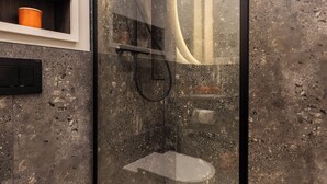 Un baño moderno con ducha de vidrio, inodoro blanco y pared con azulejos de mármol.