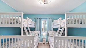 A children's room with bunk beds, teal walls, and a wooden floor. - Ocean Garden Villas J1- 2BR/2BA- Pool (North Myrtle Beach)