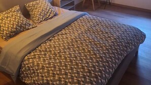 Een slaapkamer met een bed, een bureau en een stoel. Er is een raam dat natuurlijk licht biedt.