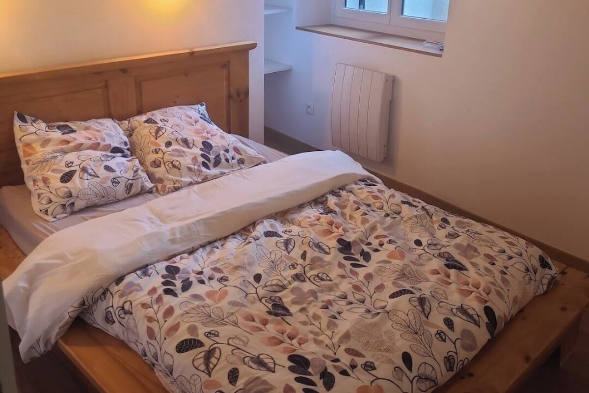 A bedroom with a wooden bed, a night light, a window, and a radiator.
