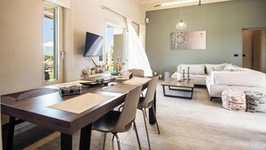 A spacious living area with a dining table, chairs, a sofa, and a television.