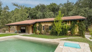 A house with a swimming pool, a covered patio, and a lush garden.