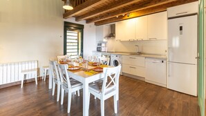 A modern kitchen with white appliances, wooden beams, and a dining area with a table set for four.